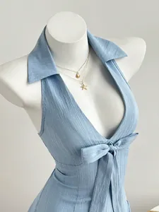 Close-up detail of light blue textured halter dress with V-neck and front bow tie