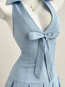 Close-up detail of light blue halter neck dress featuring bow tie and crinkle texture