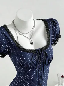Close-up detail of navy blue polka dot shirt featuring square neck and black lace trim