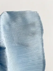 Macro view showing the textured light blue fabric and fine stitching of the summer dress.