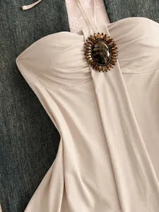 Détail d'un haut licou beige vintage avec une broche décorative en pierre