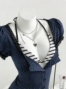 Detail view of navy blue polka dot shirt with black lace trim and heart necklace