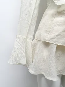 Detailed view of white crinkled chiffon fabric with ruffled sleeve and layered hemline