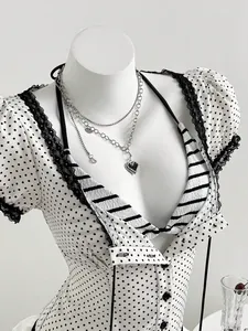 Close-up detail of white polka dot short sleeve blouse with black lace trim on mannequin