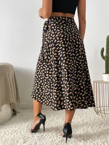 Vista trasera de falda midi negra sexy con estampado de pétalos beige y detalle de lazo