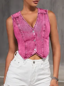 Nahaufnahme der gewaschenen Denim-Textur und der Metallknöpfe einer rosa V-Weste