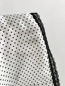 Detail view of white polka dot fabric with delicate black lace trim for women shirt.