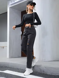 Full body street style detail of black loose-fit ripped jeans with cropped long-sleeve top