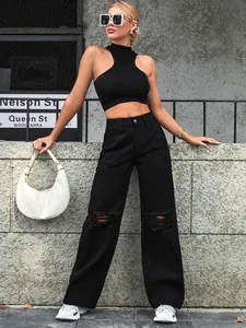 Detail shot of black wide-leg distressed denim jeans styled with sleek white accessories.