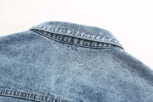 Close-up view of vintage light blue washed denim jacket collar and stitching details