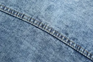 Macro detail shot of blue washed denim fabric showing vintage texture and yellow stitching.