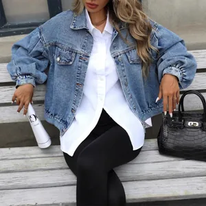 Stylish women's loose short denim jacket in light blue wash on a lifestyle model.