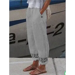 Dettaglio pantaloni in lino grigio da donna con polsini in pizzo e tasche laterali