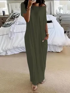 Lifestyle view of model wearing a dark olive green short sleeve loose maxi dress with pockets
