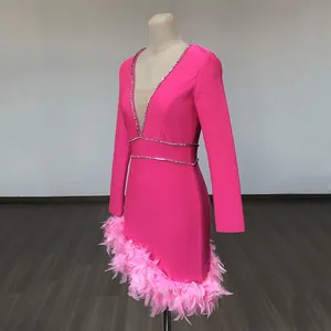 Side view of hot pink long sleeve mini dress with feather hem and rhinestone neckline trim.