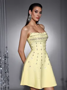 Detailed view of yellow strapless cocktail dress with heavy rhinestone embellishments