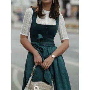 Nahaufnahme eines traditionellen dunkelgrünen Dirndls mit weißer Bluse aus Spitze