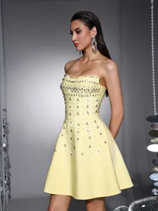 Elegant side profile of a yellow strapless cocktail dress with intricate rhinestone beads