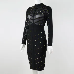 Black long-sleeved bandage dress featuring sheer mesh inserts and gold stud detailing.