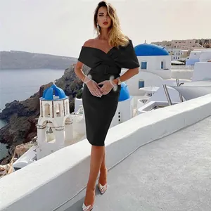 Elegant black off-the-shoulder cocktail dress with waist belt worn by a model in Santorini