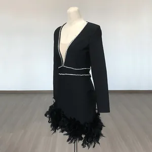 Detail view of deep V-neck bandage dress with rhinestone trim and black feather hemline