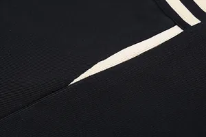 Macro view of high-quality black ribbed bandage dress fabric featuring cream contrast trim
