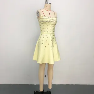 Elegant yellow strapless bandage evening dress with heavy rhinestone beading on mannequin