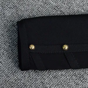 Close-up of black bandage dress sleeve featuring two elegant gold decorative buttons