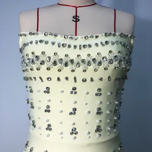 Detailed close-up of a yellow bandage dress with heavy rhinestone and pearl embellishments