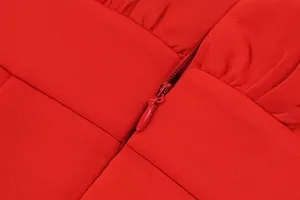 Detailed macro view of a color-matched invisible zipper on a red scuba cocktail dress