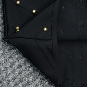 Close-up of golden stud embellishments on high-quality black bandage dress fabric