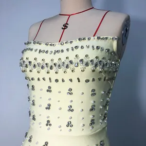 Close-up detail of heavy rhinestone and pearl embellishments on a luxury yellow bandage dress