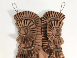 Detailed view of brown bandage dress with pleated ruffles and intricate beadwork