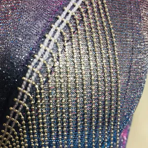 Gros plan sur un tissu métallique scintillant avec des détails de franges en perles