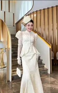 Elegante completo in pizzo bianco con collo alto e maniche a sbuffo su modella asiatica