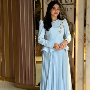 Elegant light blue pleated dress with long sleeves and gold floral embroidery detail.