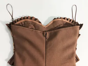 Close-up detail of a brown bandage dress featuring back zipper ruffles and beads