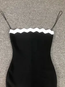 Dettaglio di un abito bandage nero aderente con bordo smerlato bianco e spalline sottili.
