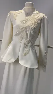 Détail de la broderie florale 3D et des paillettes sur l'ensemble robe longue de couleur ivoire