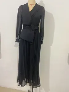 Detailed view of black pleated fashion two-piece set with belted waist and fringe.