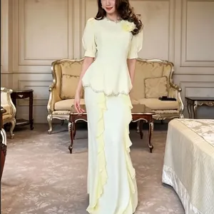 Elegant pale yellow mermaid evening gown featuring a beaded peplum top and ruffled skirt.
