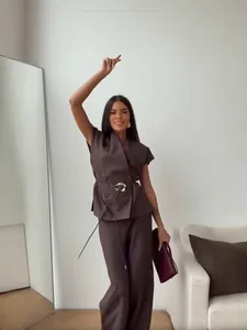 Detail view of a model wearing a brown sleeveless blazer and high-waist pants set