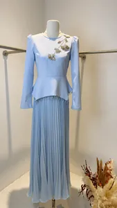 Detail view of light blue pleated long sleeve dress with floral beadwork and peplum waist