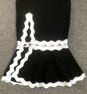 Dettaglio di un abito bandage nero con bordo in pizzo a zig-zag bianco e fondo a sirena.