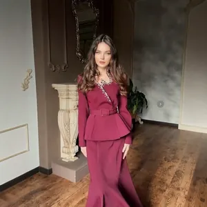 Full-body detail showing elegant burgundy peplum suit set with rhinestone V-neckline