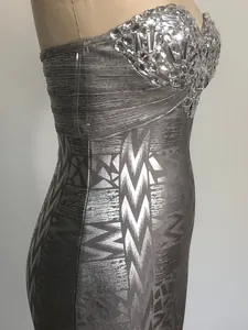 Close-up of luxurious silver bandage dress with rhinestone bust and metallic patterns.