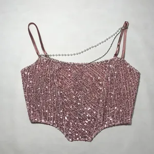 Close-up detail of a pink sequined crop top featuring elegant pearl and metal chain straps