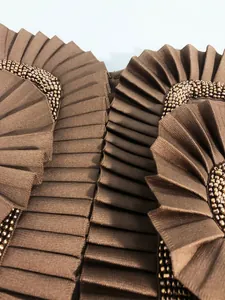Close-up of elegant pleated ruffles and intricate hand-sewn beads on a brown bandage dress.