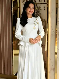Elegant white long sleeve pleated dress with intricate gold floral embroidery detail