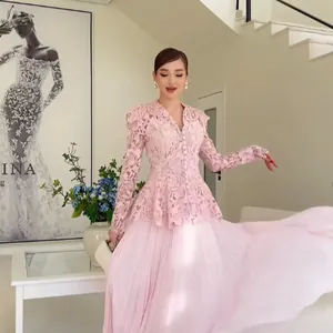 Elegant pink two-piece lace set with long-sleeved peplum top and pleated maxi skirt.